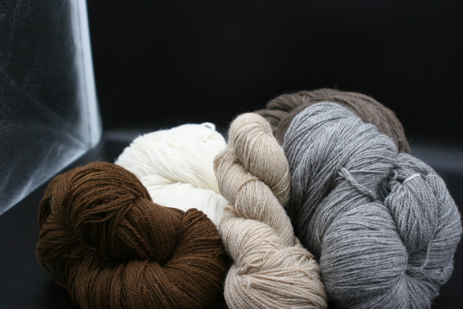 Garnstränge aus Alpakawolle in den Naturfarben Braun, Weiß, Beige und Grau